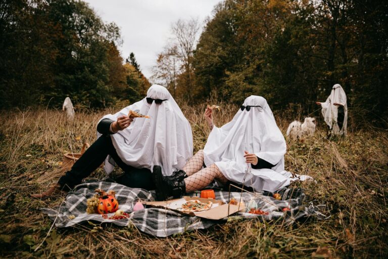 people in halloween ghost costumes having picnic in park